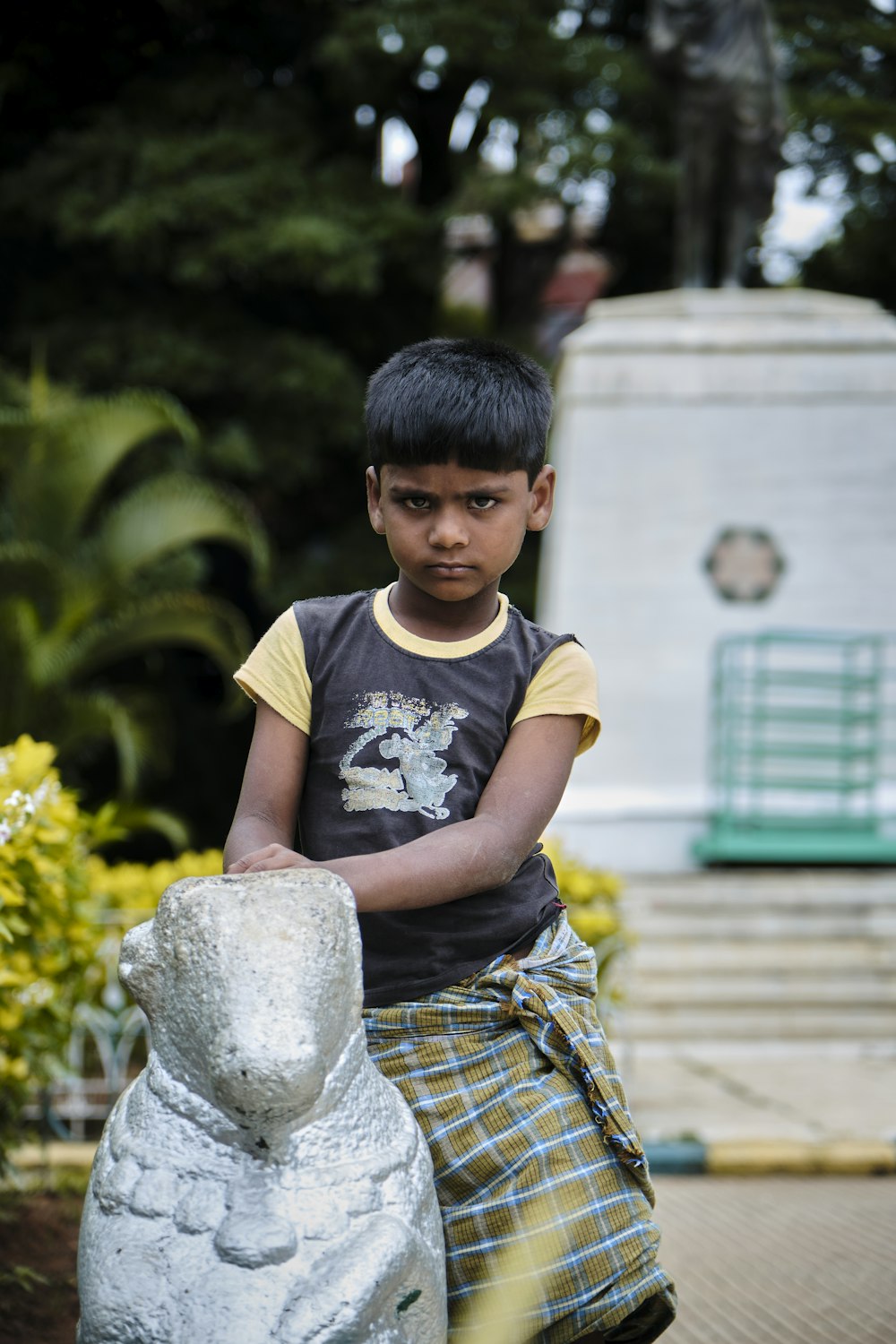 boy in black and white crew neck t-shirt sitting on gray concrete bench during daytime