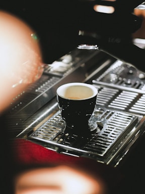 A warm cup of freshly brewed espresso on a black and white table with subtle orange and light green accents.