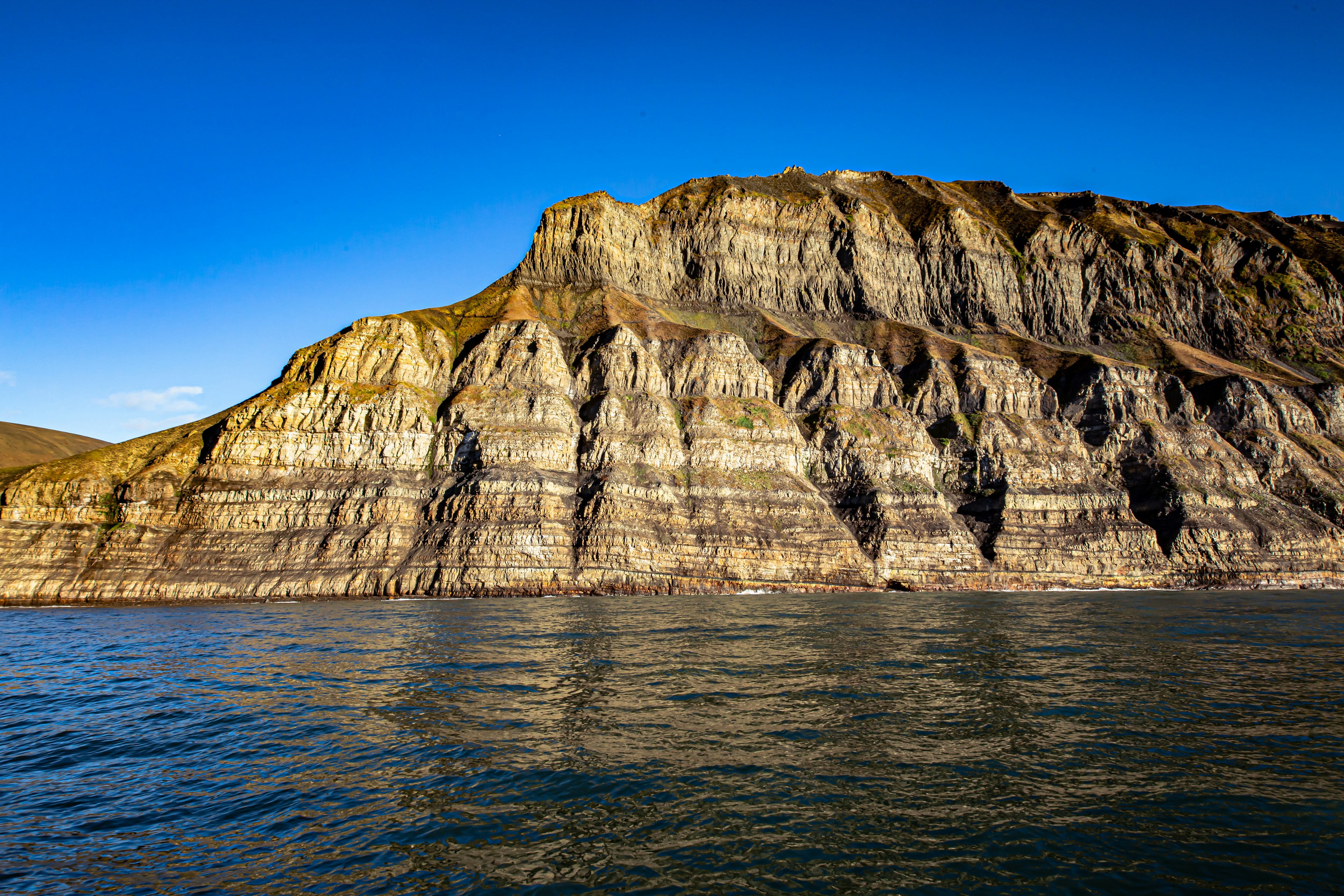 brown rocky mountain beside blue sea under blue sky during daytime, A beautiful late summer day on Svalbard (Spitsbergen) with the most spectacular nature scenery