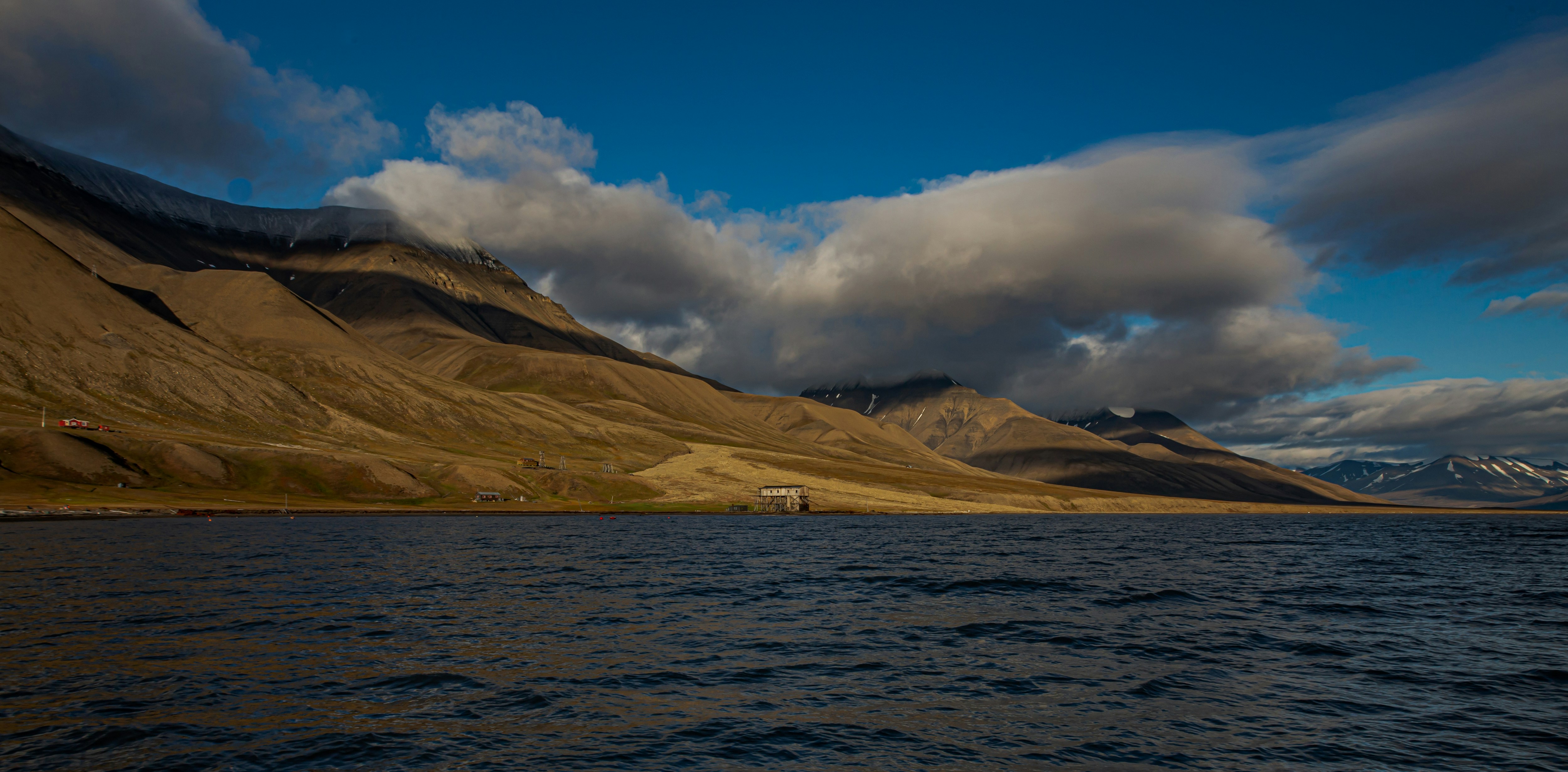 brown mountain near body of water during daytime