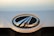 A close-up of a car emblem featuring a chrome oval shape with black and silver elements. The background appears to be a light-colored car surface with some visible specks and dirt.