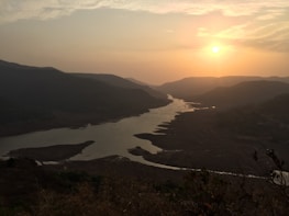 A serene river winding through lush Minas Gerais landscape at sunset.
