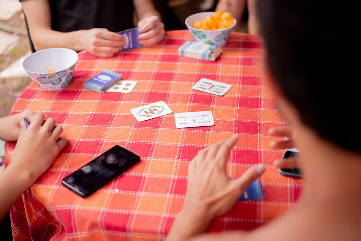 Amigos jugando a las cartas sobre un mantel rojo