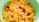 A green bowl filled with cornflakes mixed with raisins and nuts, creating a colorful and appetizing breakfast scene.