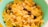 A green bowl filled with cornflakes mixed with raisins and nuts, creating a colorful and appetizing breakfast scene.