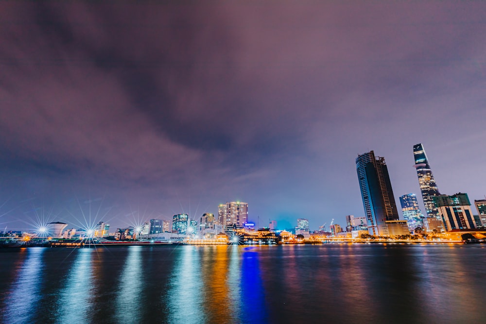 city skyline across body of water during night time