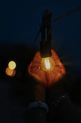 A close-up of hands sharing a light bulb to symbolize ideas about money and growth.