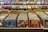 A record store display features numerous vinyl records organized in bins with labels like 'Indie Rock' and 'Punk/Hardcore.' Album covers are visible on the front of some records, while others are partially obscured. The background has shelves with more records displayed upright, and a sign that reads 'DJ Headquarters' is partially visible at the top.