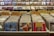 A record store display features numerous vinyl records organized in bins with labels like 'Indie Rock' and 'Punk/Hardcore.' Album covers are visible on the front of some records, while others are partially obscured. The background has shelves with more records displayed upright, and a sign that reads 'DJ Headquarters' is partially visible at the top.