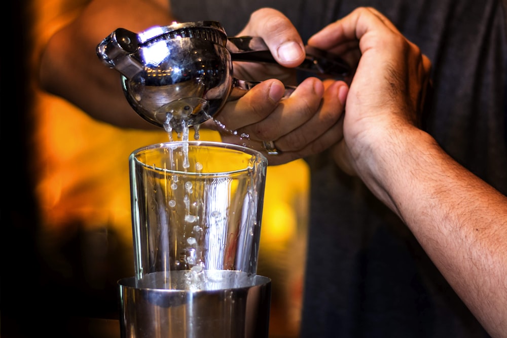 person pouring water on clear drinking glass