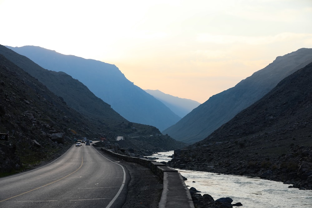 gray concrete road between green mountains during daytime