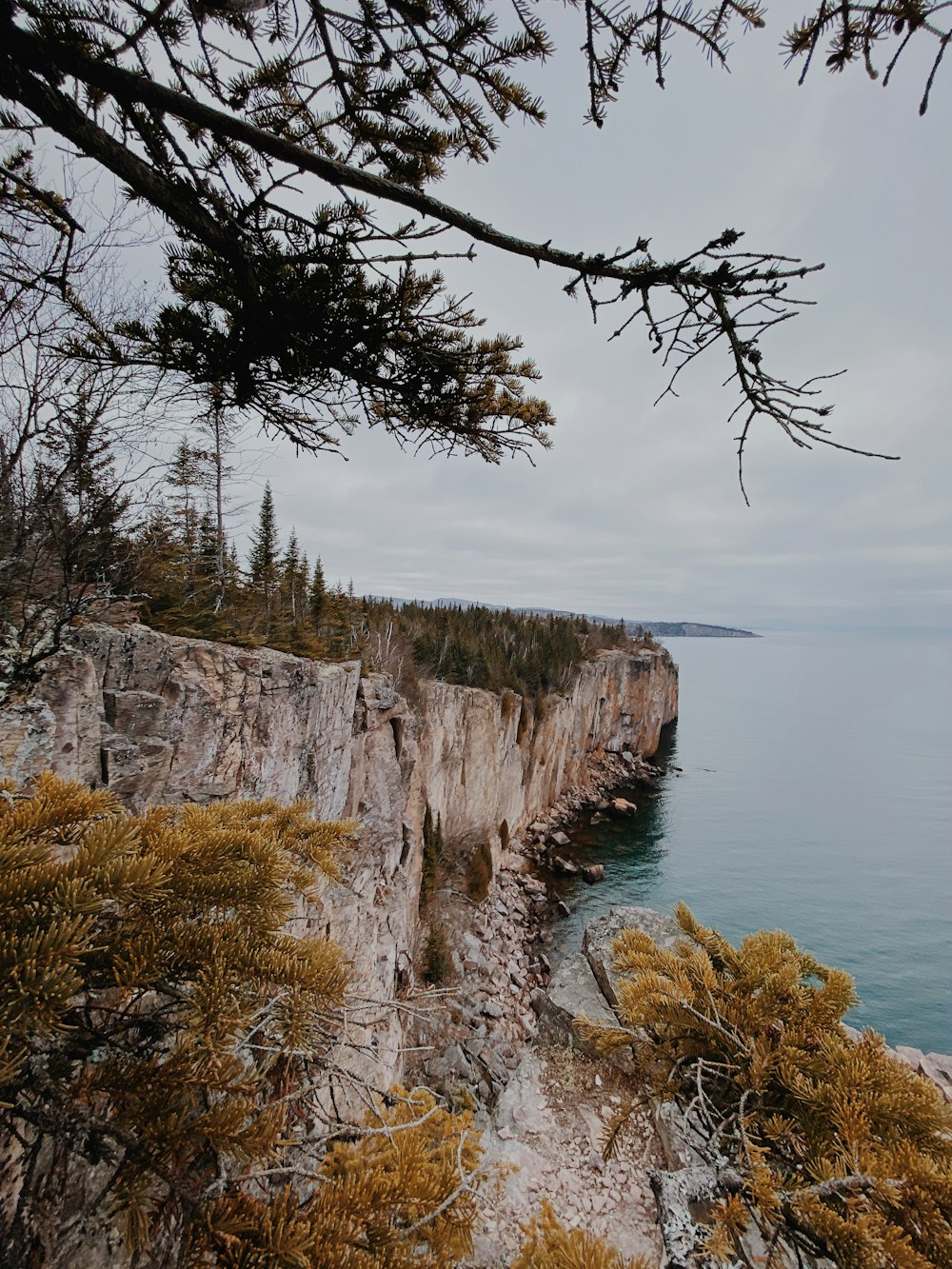 brown and gray rocky mountain beside body of water during daytime