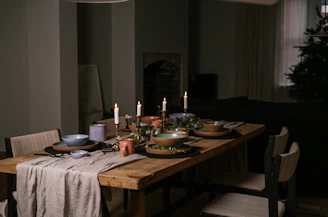 A warmly lit dining table set for a supper club, with terracotta plates and deep green accents.