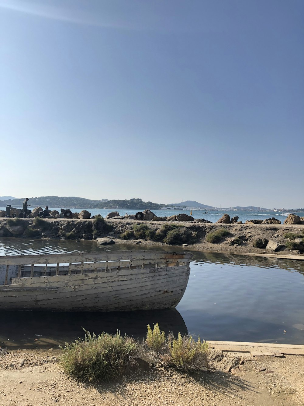 barco de madeira marrom na areia marrom perto do corpo de água durante o dia