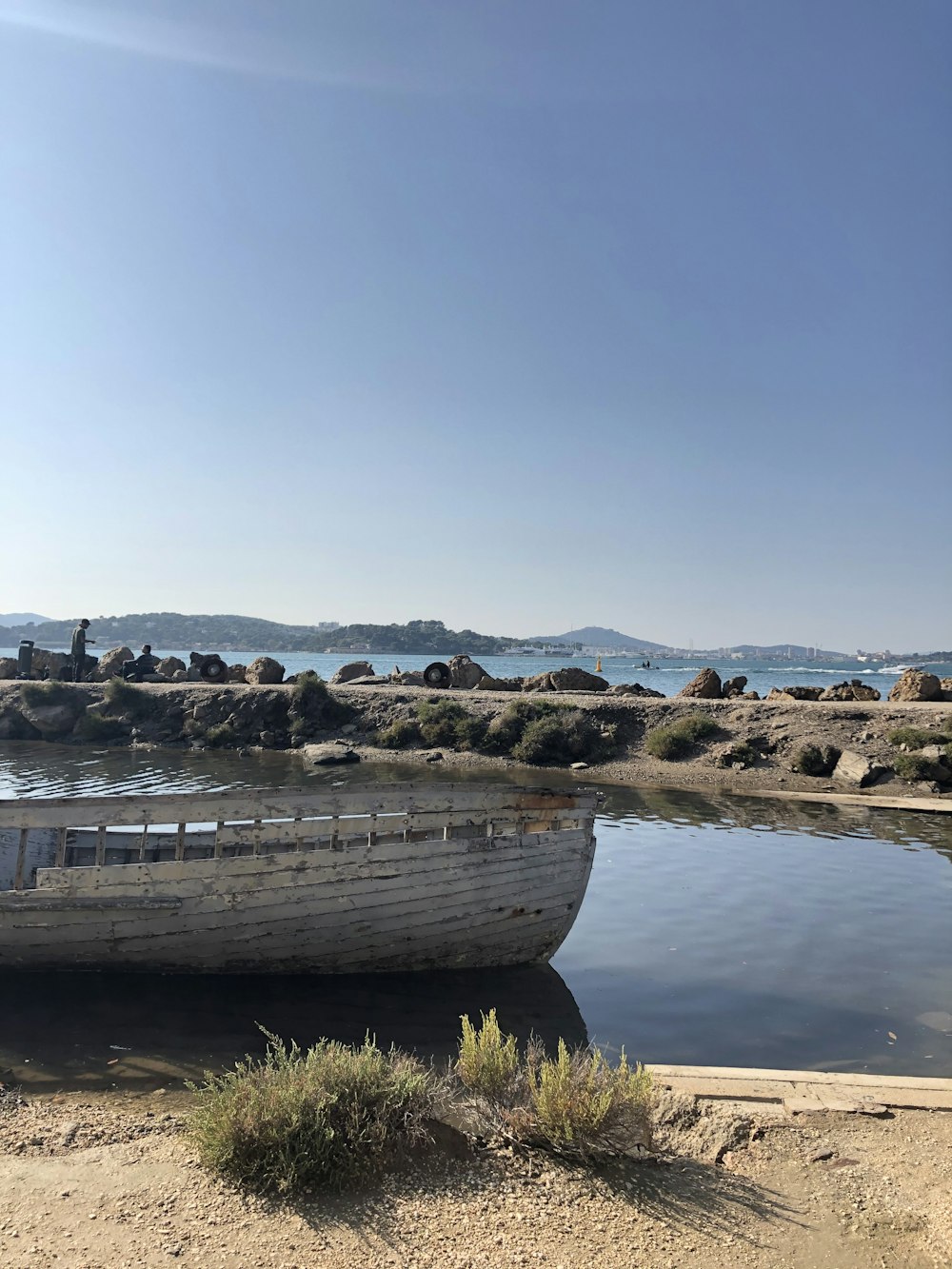 Bote de madera marrón en arena marrón cerca del cuerpo de agua durante el día