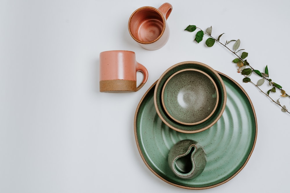 taza de té de cerámica verde en platillo al lado de la tetera