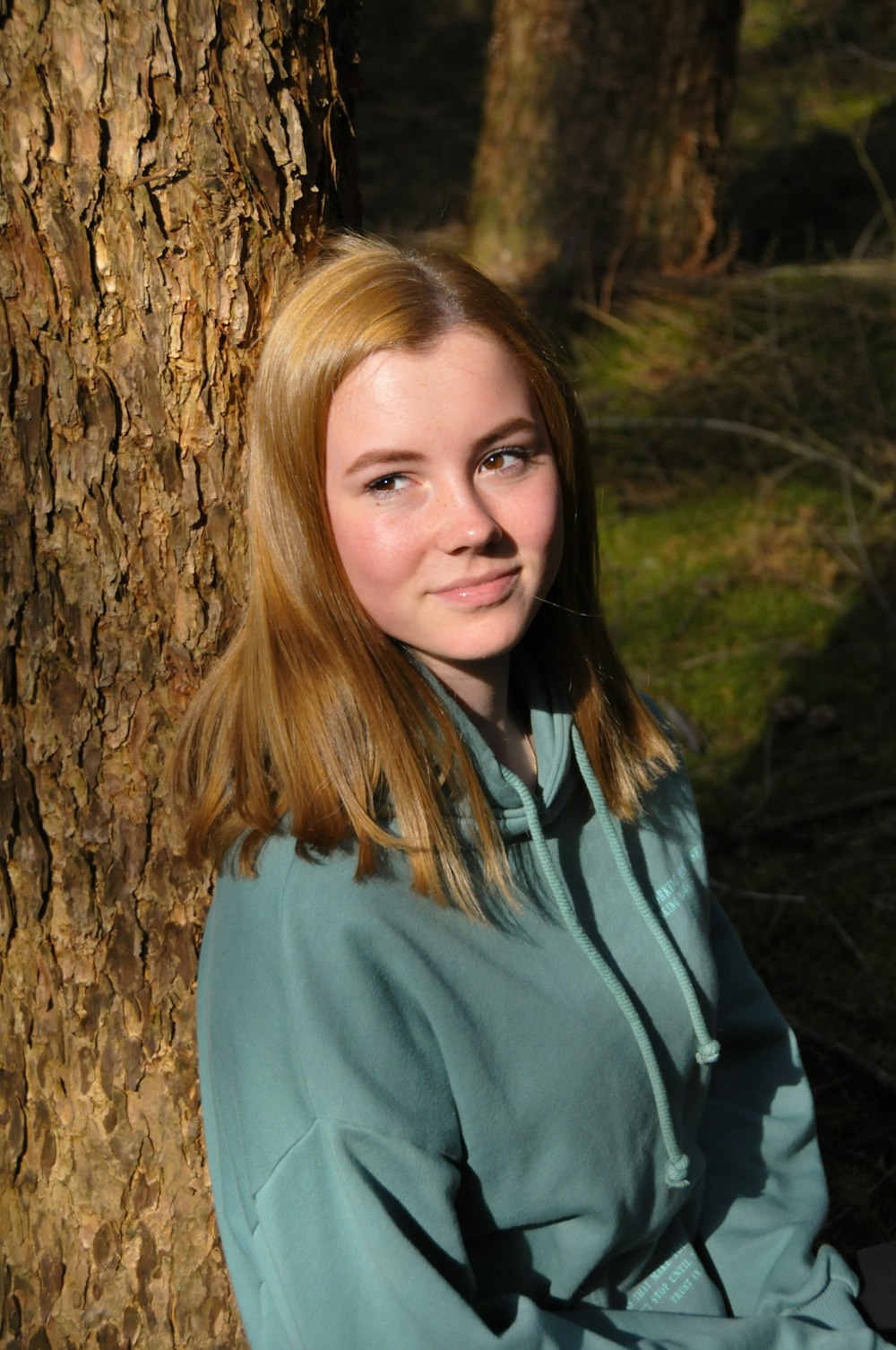 woman in blue jacket standing beside brown tree