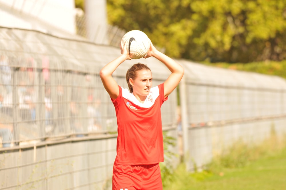 woman in red nike tank top and red shorts holding white soccer ball during daytime