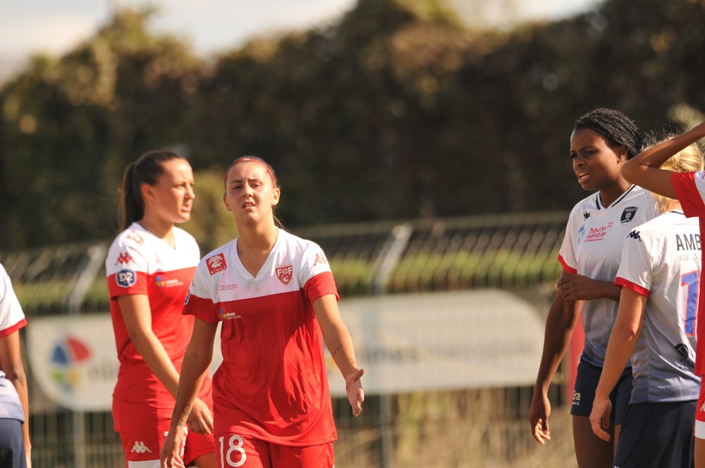 2 women in red and white soccer uniform running on field during daytime