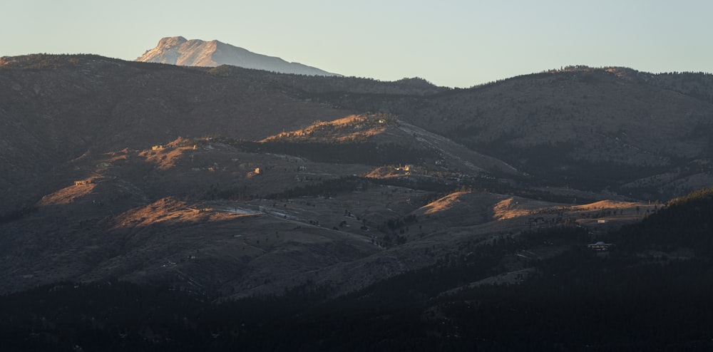 montagne marroni e verdi sotto il cielo bianco durante il giorno