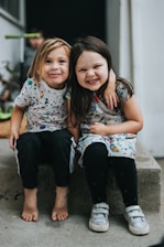 2 girls sitting on concrete floor