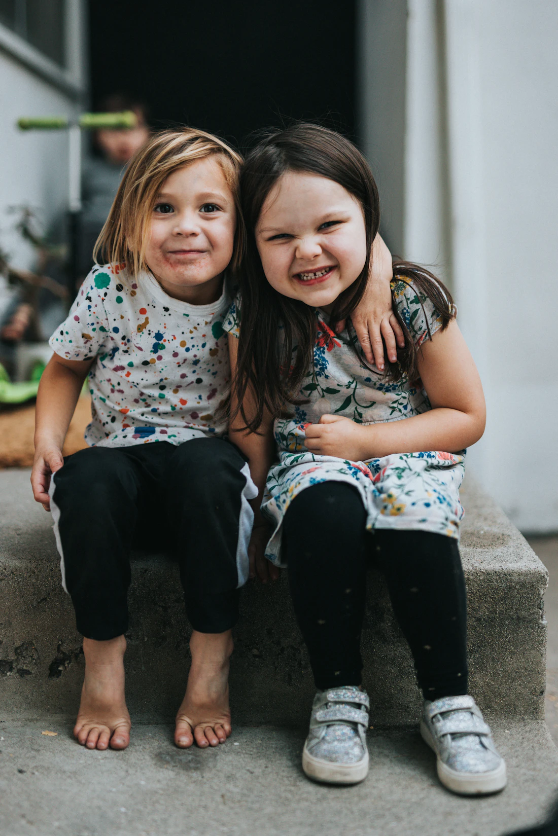 Two children sitting together on a concrete step