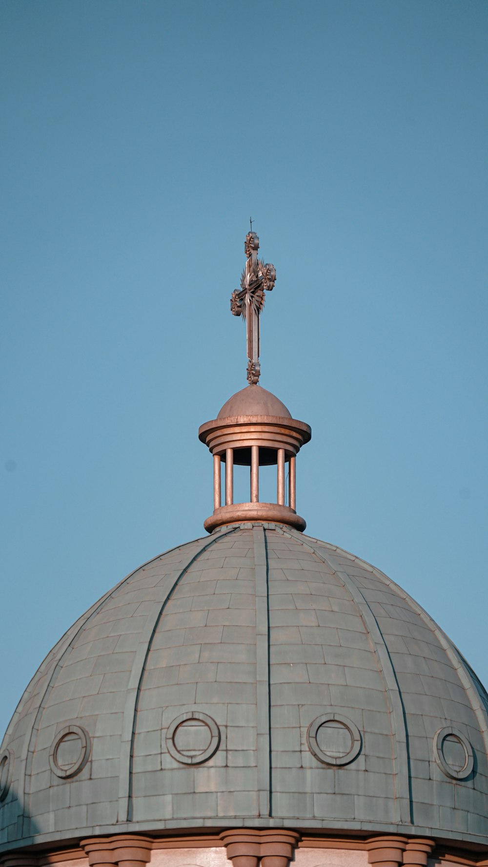 gold cross on top of gray and white dome building