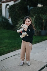 A joyful child holding a plush animal toy with a big smile.