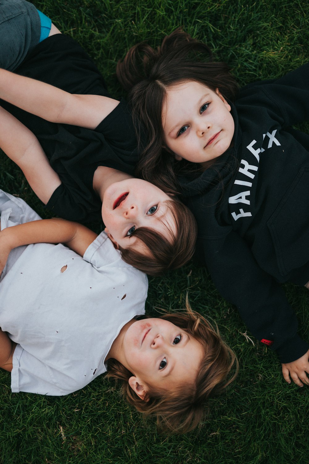 2 girls lying on green grass field