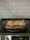 A freshly baked lasagna sits in a glass casserole dish on an electric stovetop. The kitchen backsplash features white subway tiles.