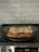 A freshly baked lasagna sits in a glass casserole dish on an electric stovetop. The kitchen backsplash features white subway tiles.