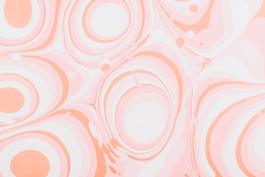 Swirling patterns of smooth, pastel-colored circles and waves create a marbled effect. The design consists primarily of soft oranges and pinks against a lighter background, giving a sense of fluidity and calm.