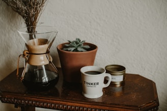 An inviting coffee setup featuring a vintage grinder, beans in a glass jar, and a small potted plant.