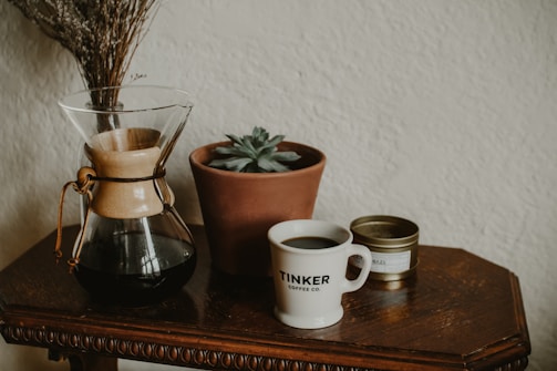 An inviting coffee setup featuring a vintage grinder, beans in a glass jar, and a small potted plant.