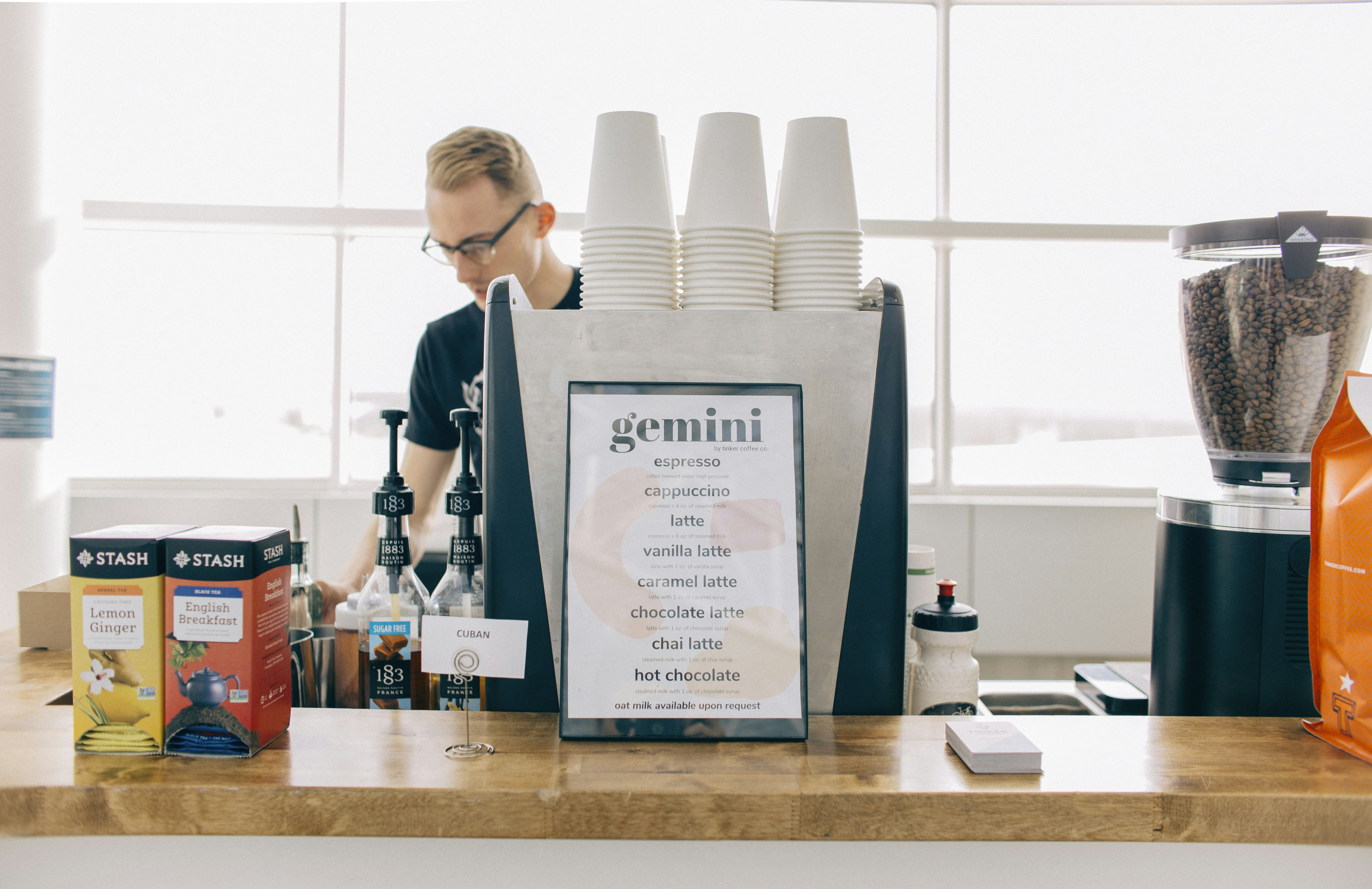 茶色の木製のテーブルのそばに立つ黒と白のシャツを着た女性