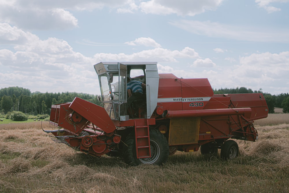 red and black heavy equipment on brown field under white clouds during daytime