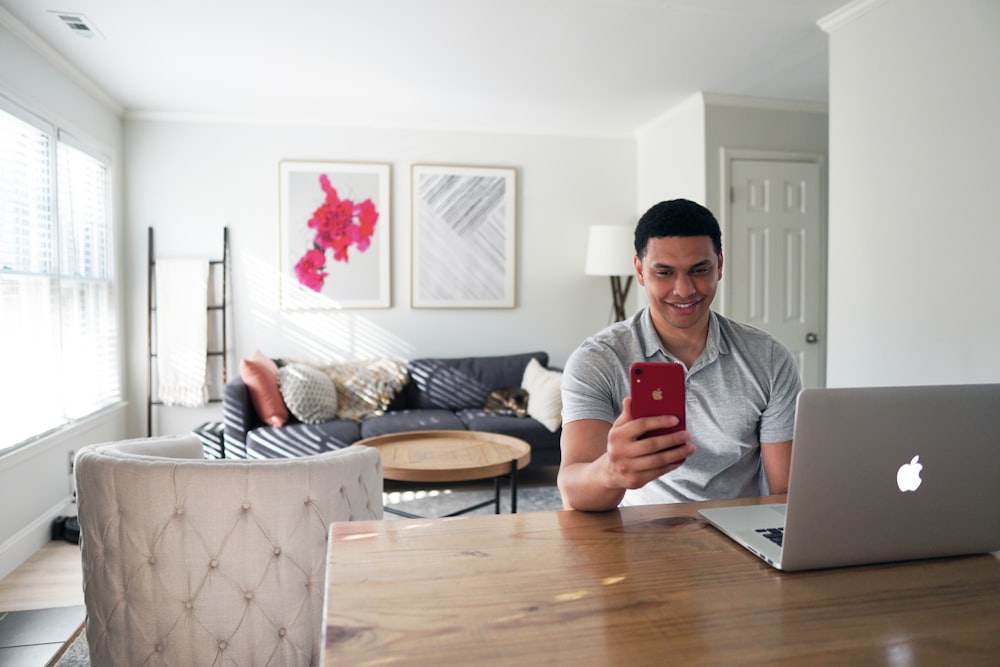 man in gray crew neck t-shirt holding red iphone case