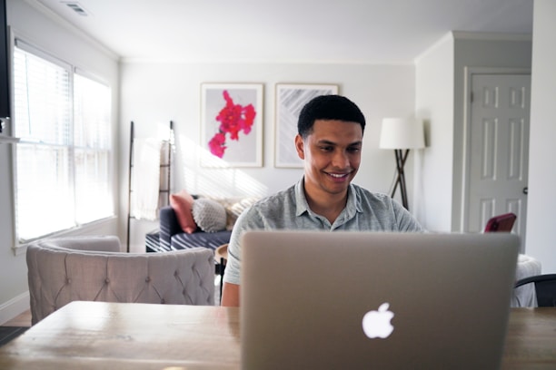 A happy student using a laptop while sitting in a cozy room, symbolizing online insurance service.