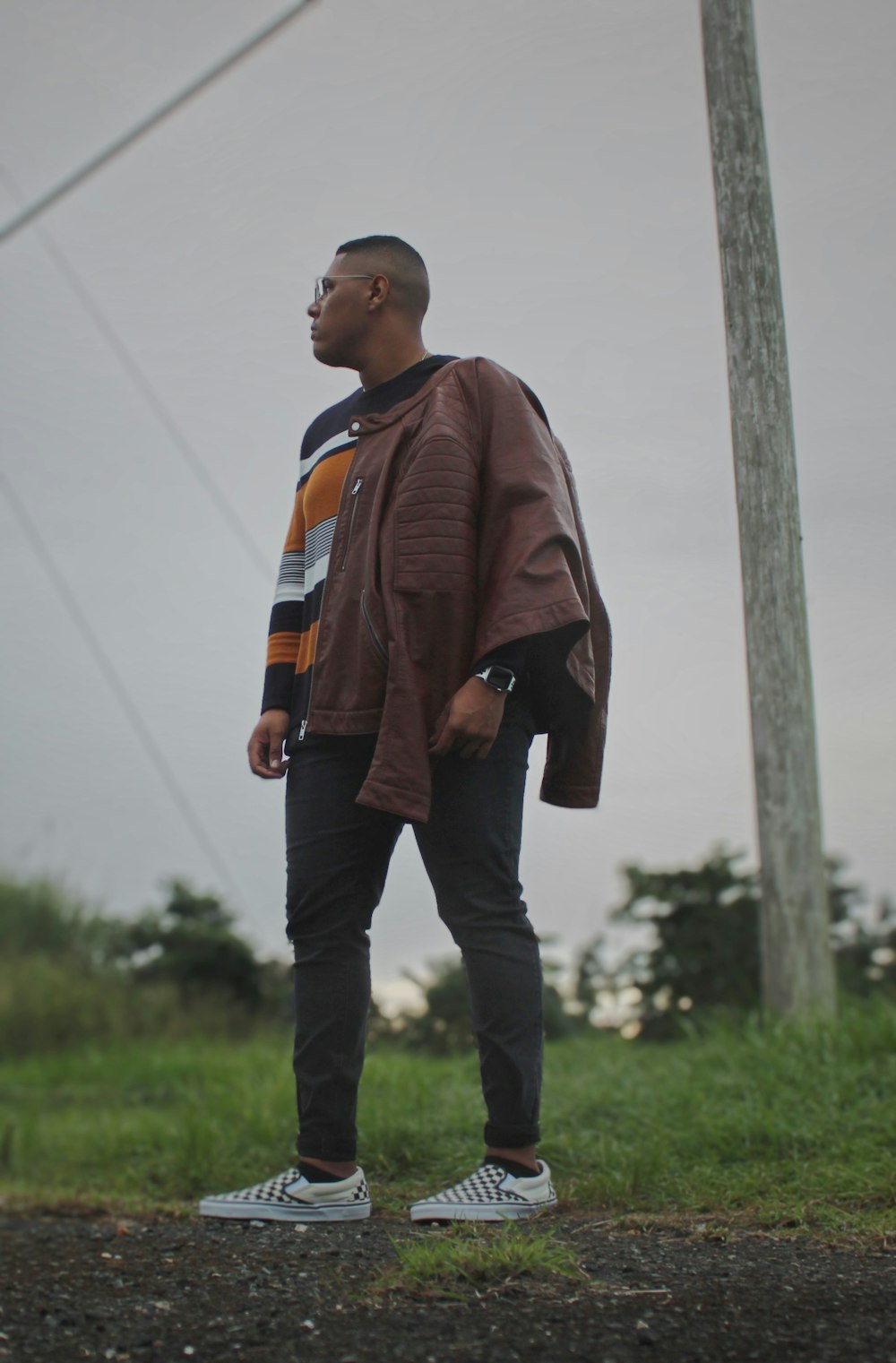 man in black and orange jacket standing on green grass field during daytime