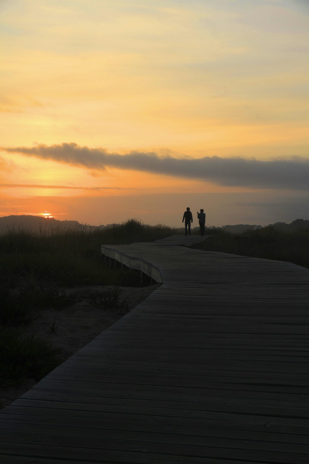 silhouette of 2 person walking on pathway during sunset