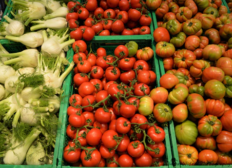 Close-up of freshly harvested seasonal vegetables arranged in wooden crates at a wholesale market.
