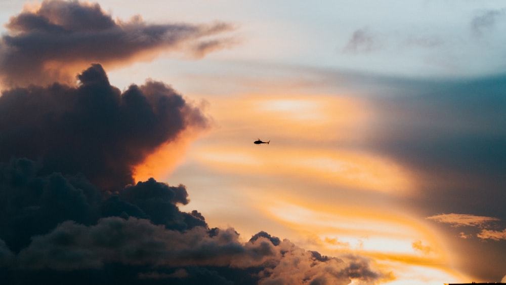 airplane flying over clouds during sunset