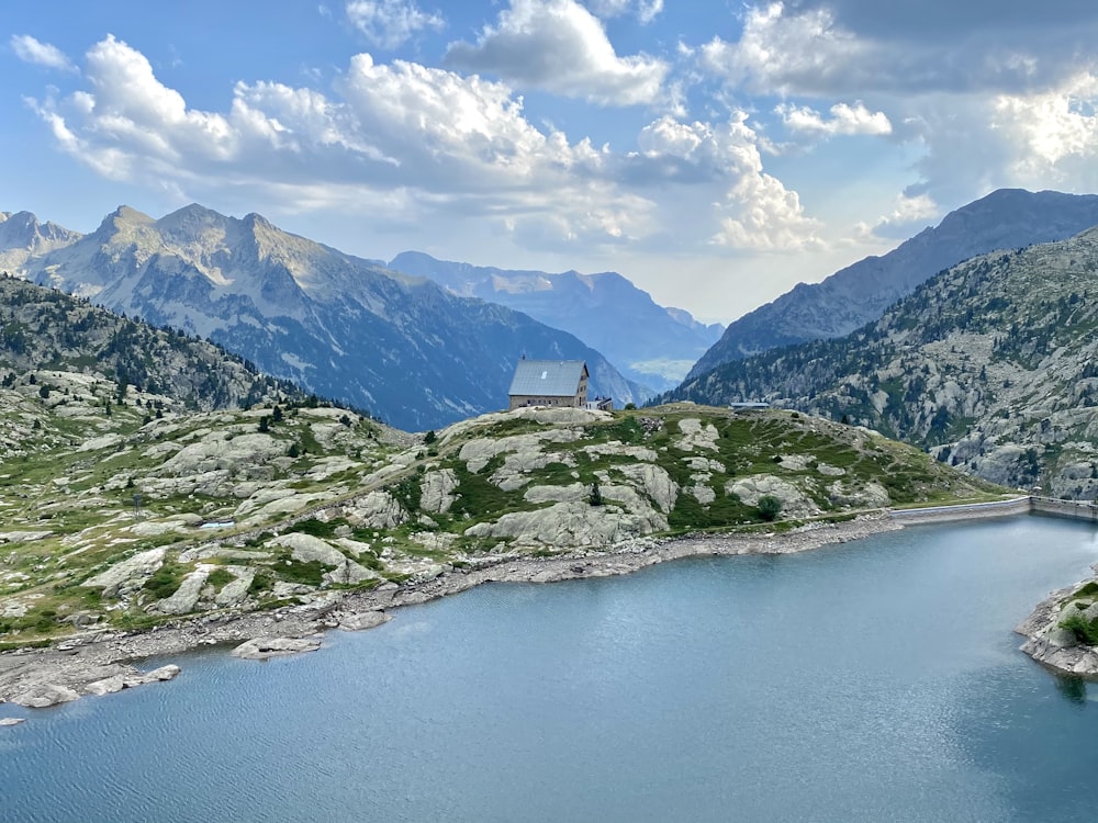 a lake surrounded by mountains under a cloudy sky