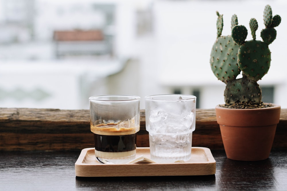 three clear drinking glasses on brown wooden tray