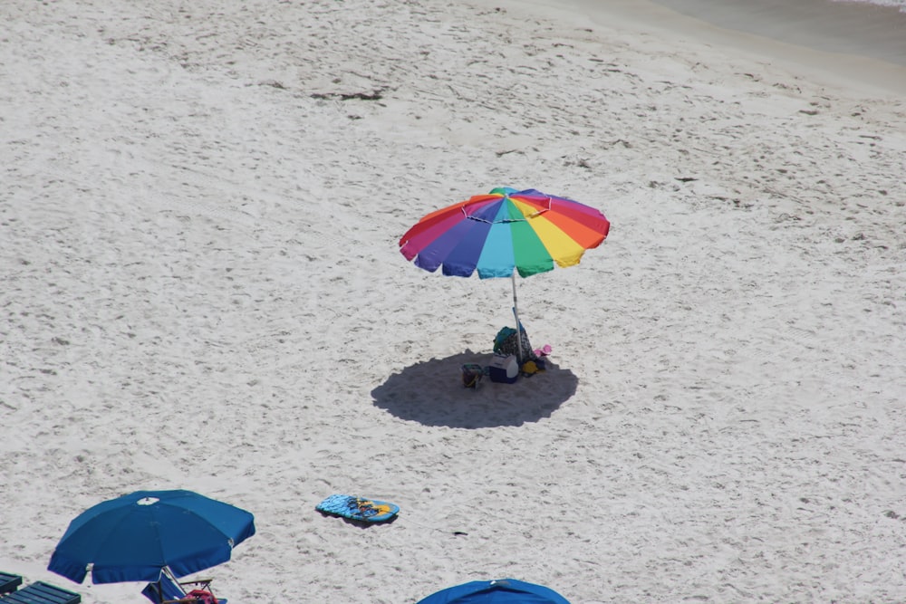 2 people standing on beach with umbrella during daytime