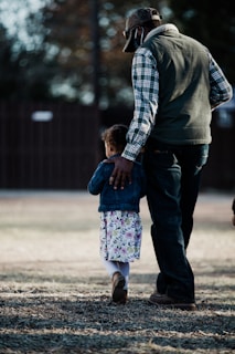 man in black and white checkered dress shirt holding girl in pink and white floral dress