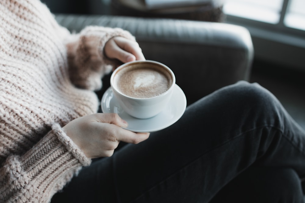 woman in white knit sweater holding white ceramic mug