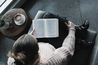 woman in white sweater reading book