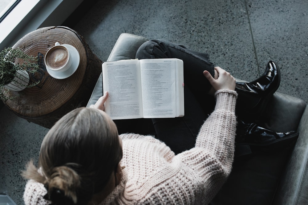 Donna in maglione bianco che legge il libro