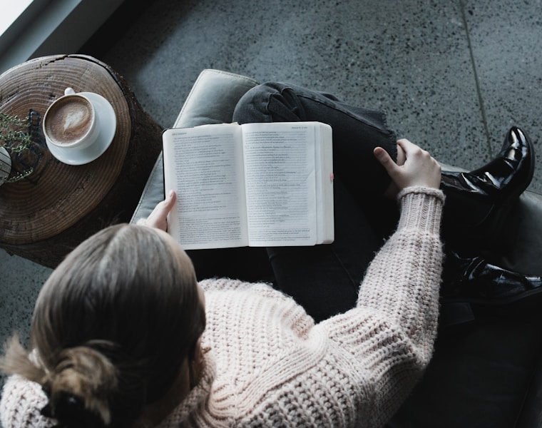 woman in white sweater reading book